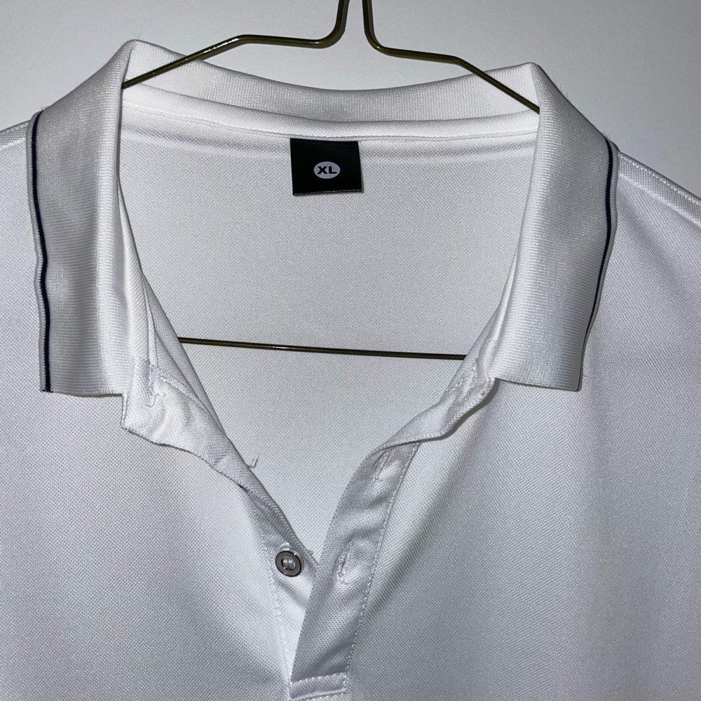 White polo with black trim around the collar and sleeves. 100% polyester.